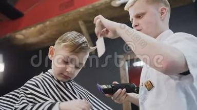 快关<strong>门</strong>。 专业理发师在山脊和电动剃须刀的帮助下做了一个新的理发。 小男孩和<strong>造型</strong>师